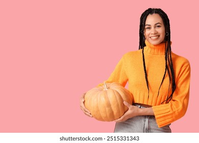 Beautiful young happy African-American woman with big orange pumpkin on pink background - Powered by Shutterstock