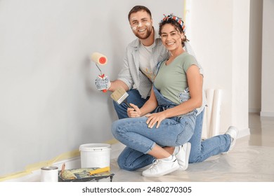 Beautiful young happy couple with paint roller and brush doing repair in new house - Powered by Shutterstock