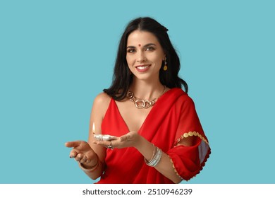 Beautiful young happy Indian woman in traditional sari with burning candle on blue background. Divaly celebration - Powered by Shutterstock