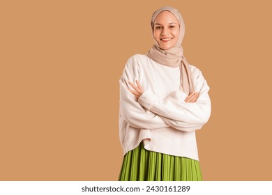 Beautiful young happy Muslim woman in hijab on brown background - Powered by Shutterstock