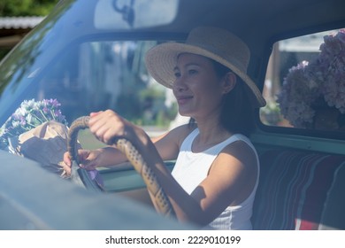 Beautiful young happy smiling woman driving her car and flower - Shutterstock ID 2229010199