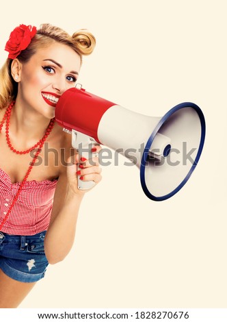 Beautiful young happy smiling woman holding megaphone. Girl in pin-up style. Caucasian model with open mouth posing in retro vintage studio concept. Advertising some thing. Ad picture image.