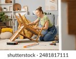 Beautiful young happy woman assembling furniture at home