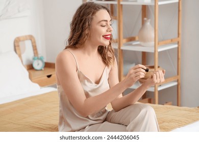 Beautiful young happy woman doing manicure in bedroom - Powered by Shutterstock