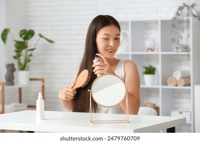 Beautiful young happy woman with hair sprays and brush at home - Powered by Shutterstock