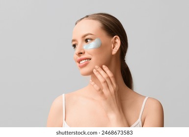 Beautiful young happy woman with healthy skin and under-eye patches on grey background - Powered by Shutterstock