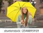 Beautiful young happy woman in raincoat with umbrella on rainy day outdoors