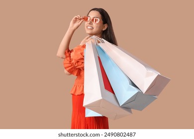 Beautiful young happy woman with shopping bags on brown background. Summer sale concept