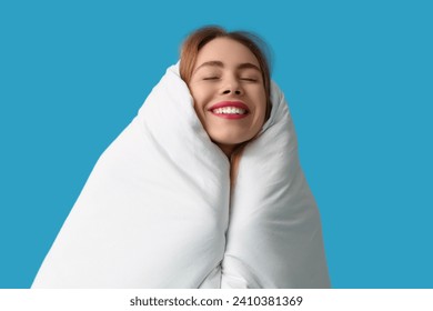 Beautiful young happy woman with soft blanket on blue background - Powered by Shutterstock