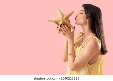 Beautiful young happy woman with starfish blowing kiss on pink background. Summer vacation concept - Powered by Shutterstock