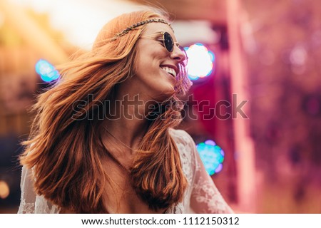 Beautiful young hippie woman enjoying at music festival outdoors. Woman in retro look dancing at music festival.