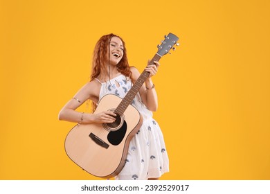 Beautiful young hippie woman playing guitar on orange background - Powered by Shutterstock