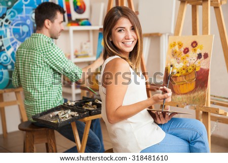 Beautiful young Hispanic woman and a handsome man attending a painting workshop together and having fun