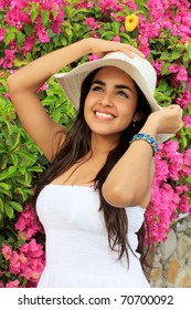 Beautiful young hispanic woman standing in front of a Bougainvillea flower garden