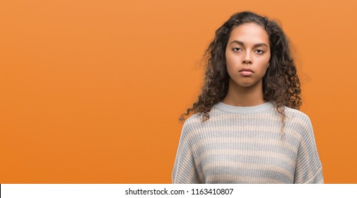 Beautiful Young Hispanic Woman Wearing Stripes Sweater With Serious Expression On Face. Simple And Natural Looking At The Camera.