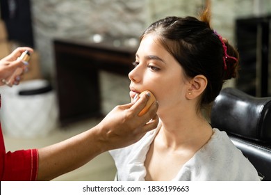 A Beautiful Young Indian Girl Gets Makeup Done At A Salon, Makeup Artist Applying Sponge On Face Of Model.