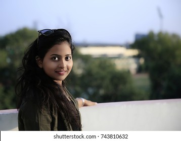 A Beautiful Young Indian woman standing on the rooftop of a skyscraper over a city