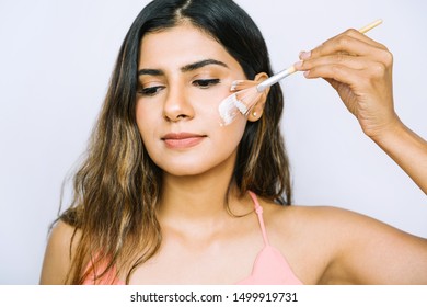 Beautiful Young Indian Woman Using Brush To Paint White Facial Cream Moisturizing Mask Lotion On Face