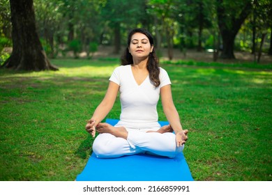 Beautiful young indian woman wearing white outfit do yoga meditation outdoor in nature Brunette female breathing exercise in park alone, fitness,  Mental health, Stress management. Copy space. - Powered by Shutterstock