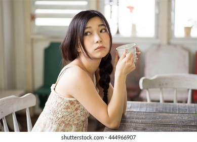 美しい日本の若い女性が家でコーヒーを飲んでいる