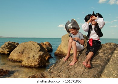 Beautiful Young Kids Pirate Boy And Girl Holding A Pirate Map And A Magnifying Glass Looking For Buried Treasure On The Beach