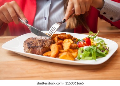 Beautiful young lady alone in restaurant eating food and using her laptop