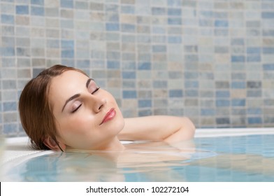 Beautiful young lady relaxing during a bath in a pool at thermal club