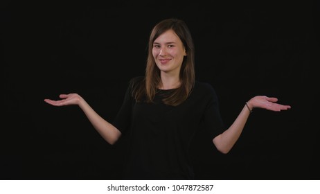 A beautiful young lady spreading her arms against a black background. Medium Shot