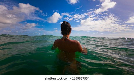 A beautiful young latin Brazilian woman in a bikini, standing in the middle of a gorgeous green tropical water beach in Tabatinga, Brazil near Joao Pessoa.