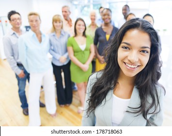 Beautiful Young Latin Woman Standing In Front of Crowd at Office
