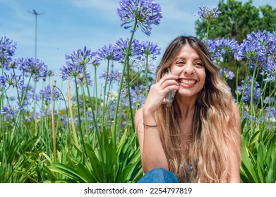beautiful young long haired latin colombian woman, wearing blue clothes, smiling, happy talking on the phone with her boyfriend, on a call outside in the park, technology concept, copy space. - Shutterstock ID 2254797819