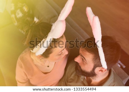Beautiful young loving couple bonding to each other with pink rabbit ears on head. Happy family preparing for Easter