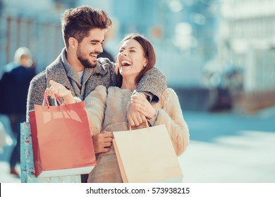 Beautiful young loving couple carrying shopping bags and enjoying together.