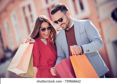 Beautiful young loving couple carrying shopping bags and enjoying together. - Powered by Shutterstock