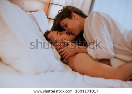 Beautiful young loving couple lying on bed in the room