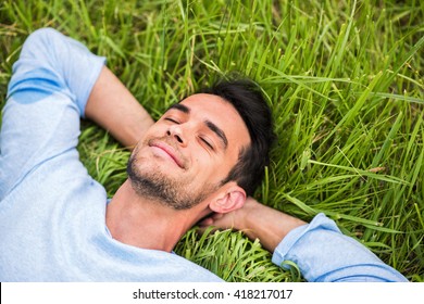 Beautiful young man with closed eyes, dreaming and relax on the green grass - Powered by Shutterstock