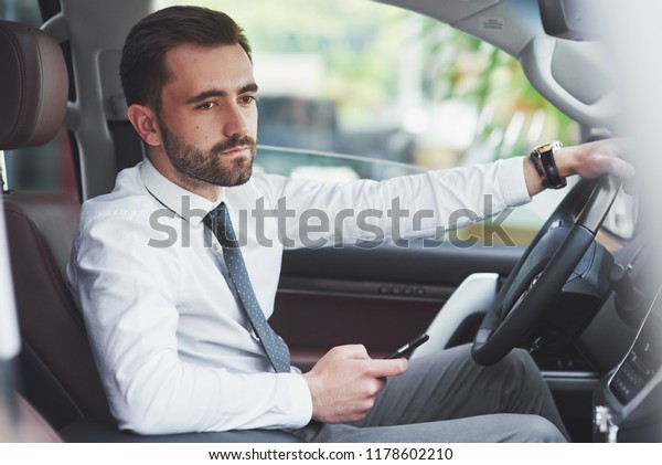 Beautiful\
young man in full suit while driving a\
car.