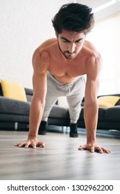 Beautiful Young Man Training And Working Out. Handsome Hispanic Male Athlete Exercising With A Chest Routine For Wellness In His Living Room. Latino People Doing Pushups And Sport At Home.