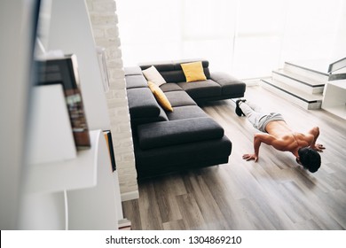 Beautiful Young Man Training And Working Out. Handsome Hispanic Male Athlete Exercising With A Chest Routine For Wellness In His Living Room. Latino People Doing Fly Pushups And Sport At Home.