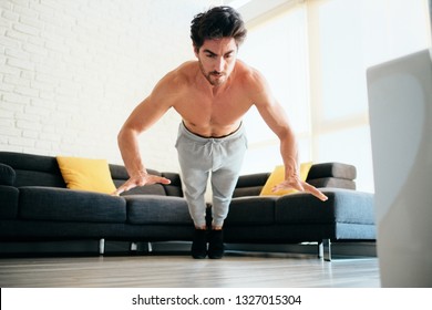 Beautiful Young Man Training And Working Out. Handsome Hispanic Male Athlete Exercising With A Chest Routine For Wellness In His Living Room. Latino People Doing Explosive Pushups And Sport At Home.