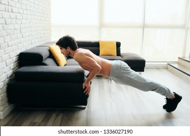 Beautiful Young Man Training And Working Out. Athlete Exercising With A Chest Routine For Wellness In His Living Room. Latino People Doing Push-ups With Backward Grip Using Sofa At Home.