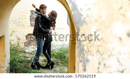Beautiful young man and woman hugging, standing in the arch of the old dilapidated building. Place for text