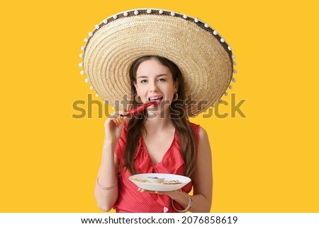 Beautiful young Mexican woman with tasty quesadilla and chili pepper on color background