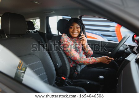 Beautiful young mixed race black African American woman driving car and speaks by phone