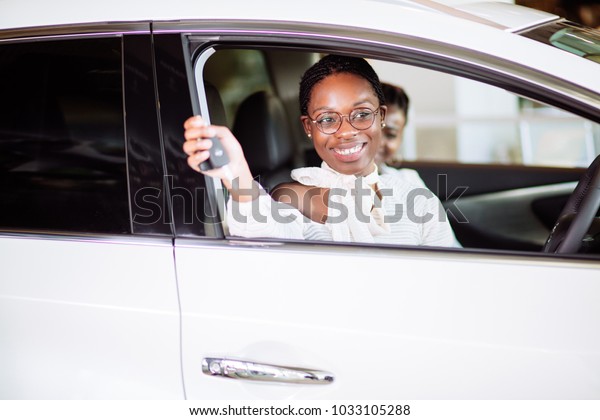 Beautiful young mixed race black African\
American woman driving car and show holding the\
key