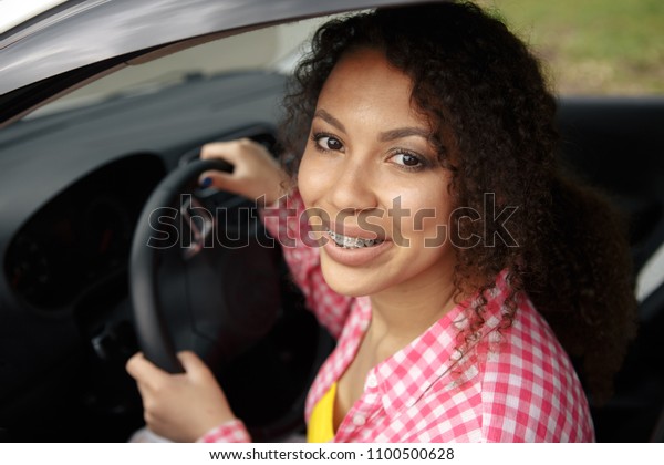 Beautiful young mixed race black African\
American woman driving a car and holding the\
key