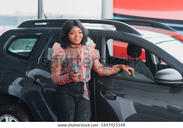 Beautiful young mixed race black African\
American woman driving car and show holding the\
key