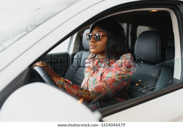 Beautiful young mixed race black African\
American woman driving car and speaks by\
phone