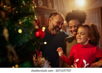 Beautiful young mixed race family enjoying their holiday time together, decorating Christmas tree, arranging the christmas lights and having fun