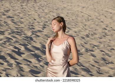 Beautiful young model in camisole beige silk satin long dress, fashion summer portrait on the beach